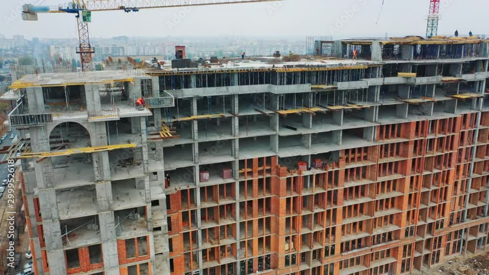 Massive residential building at construction site. Drone aerial view of new development with cityscape. Wide view of a new building with urban city behind. Massive residential building at construction site. Drone aerial view of new development with cityscape. Wide view of a new building with urban city behind.