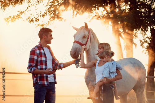  Smiling family have a fun with a beautiful horse on the countryside . photo