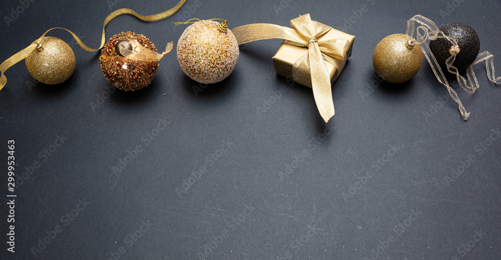 Xmas present and bauble shiny gold color against grey black background Xmas present and bauble shiny gold color against grey black background