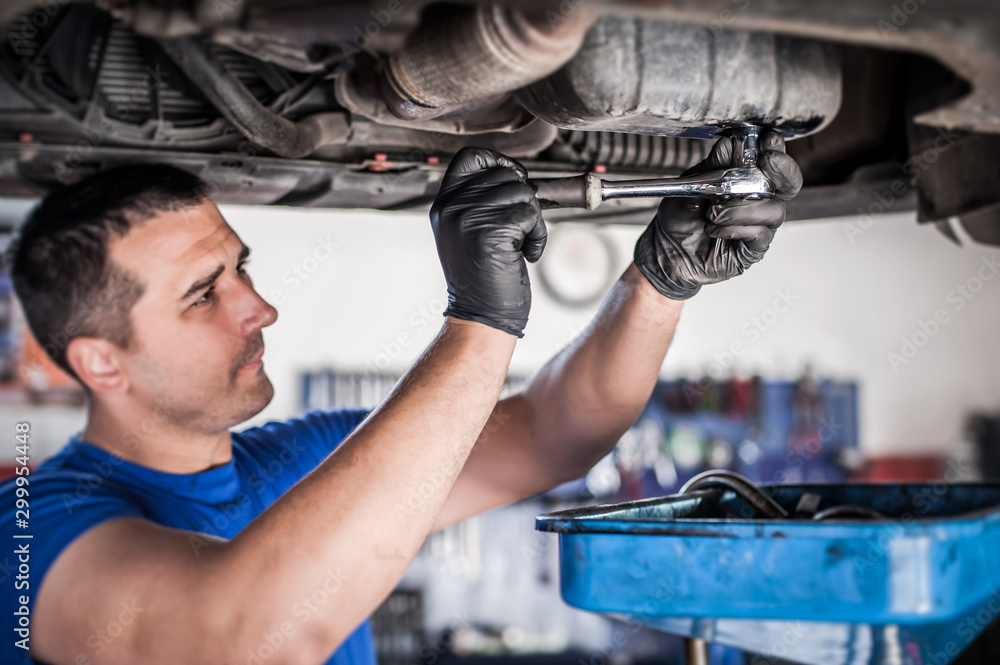 Mechanic discharges motor oil from engine tank under the car Stock