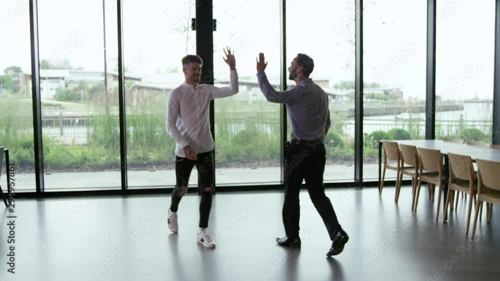 Bullet time shot of businessmen giving a high five in creative office Bullet time shot of businessmen giving a high five in creative office
