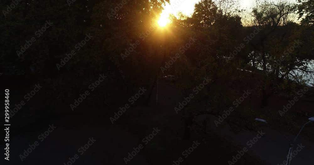 Aerial scene flying near tree brunches and leaves sunset between vegetation, discovering river and wild lanscape with sun at horizon. San Salvador river, Dolores city, Soriano, Uruguay Aerial scene flying near tree brunches and leaves sunset between vegetation, discovering river and wild lanscape with sun at horizon. San Salvador river, Dolores city, Soriano, Uruguay