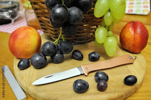 Folding knife and fresh organic ripe fruits peaches grape natural gourmet product dessert 