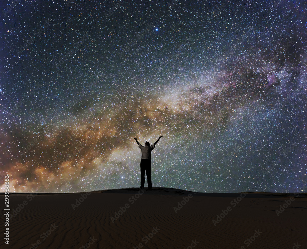 man with hangs up under a starry sky with milky way, night prayer