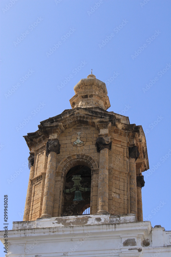 The bell tower of the historical city hall building of Cadiz at Saint John of God square (Plaza San Juan de Dios) in Andalusia, southern Spain. It was built in 16th century. The bell tower of the historical city hall building of Cadiz at Saint John of God square (Plaza San Juan de Dios) in Andalusia, southern Spain. It was built in 16th century.