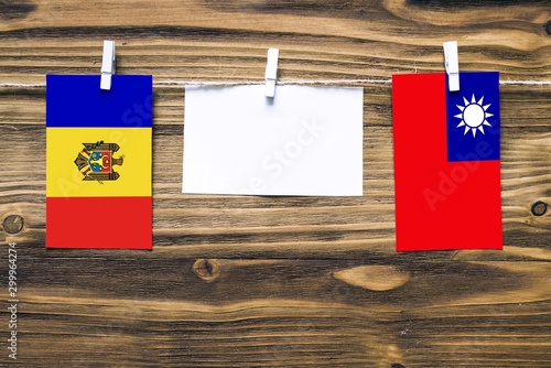 Hanging flags of Moldova and Taiwan attached to rope with clothes pins with copy space on white note paper on wooden background.Diplomatic relations between countries.