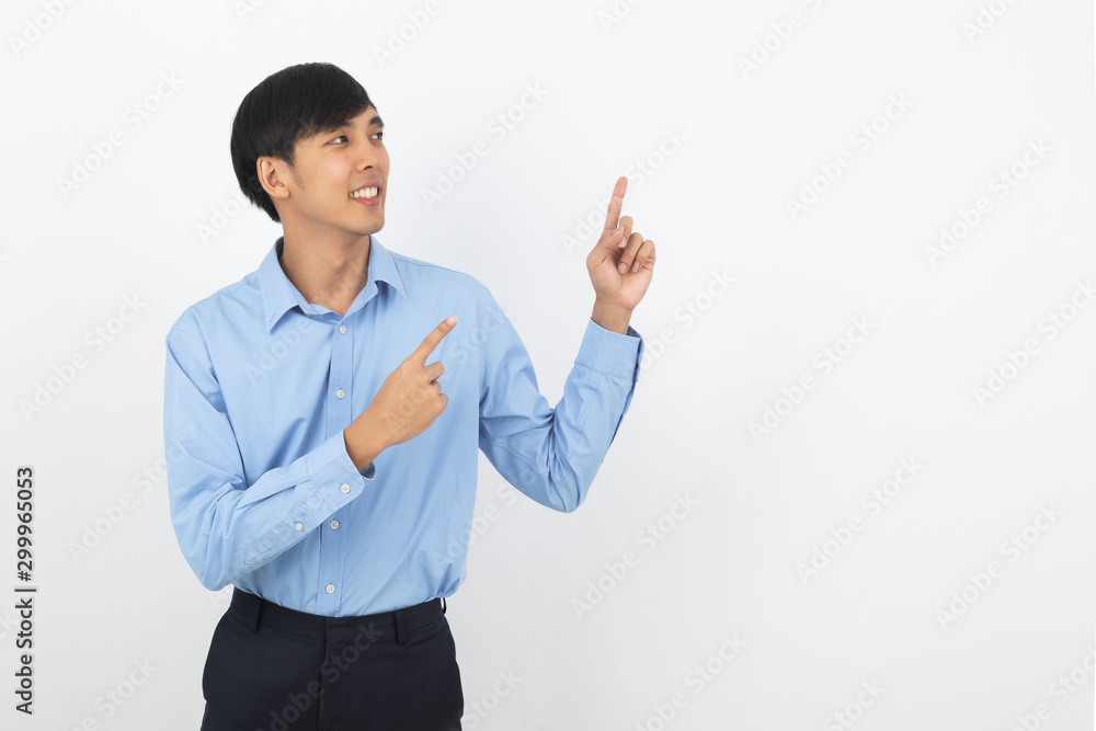 Young asian business man with blue shirt pointing to the side with a finger to present a product or an idea while looking forward smiling isolated on white background. Young asian business man with blue shirt pointing to the side with a finger to present a product or an idea while looking forward smiling isolated on white background.