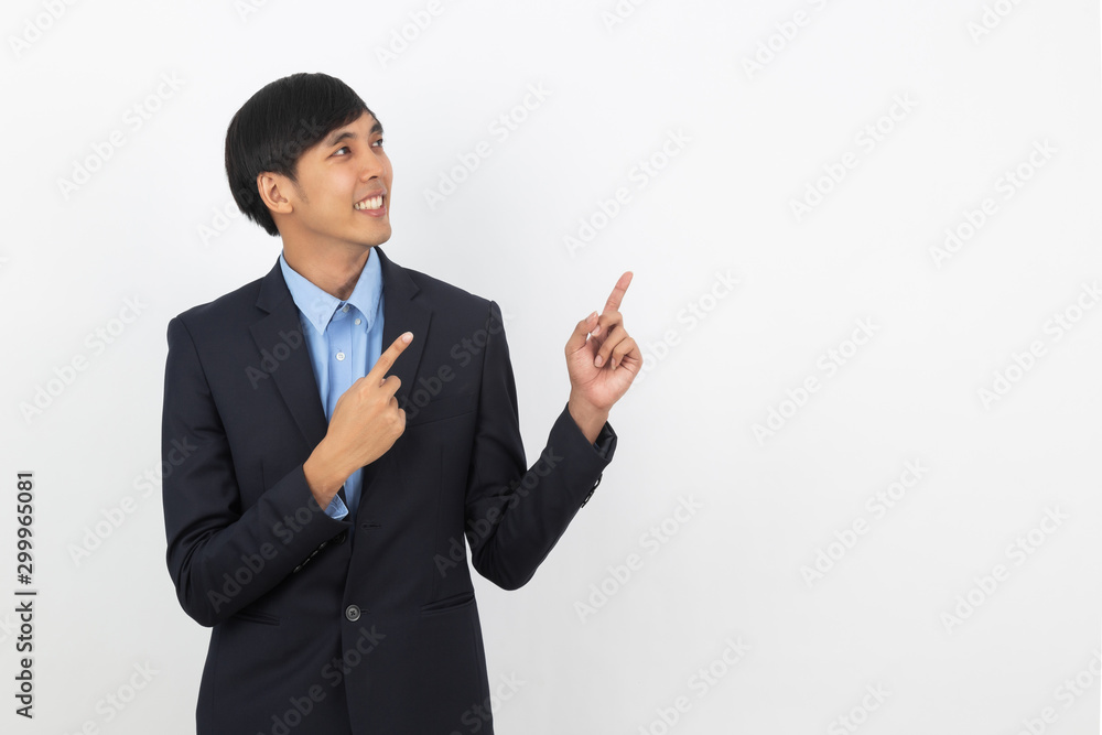 Young asian business man pointing to the side with a finger to present a product or an idea while looking forward smiling isolated on white background. Young asian business man pointing to the side with a finger to present a product or an idea while looking forward smiling isolated on white background.