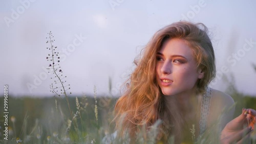 Beautiful girl lying on the meadow and dreaming. Enjoy nature. Slow motion footage