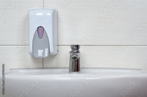Seifenspender an der Wand mit Wasserhahn und Waschbecken
