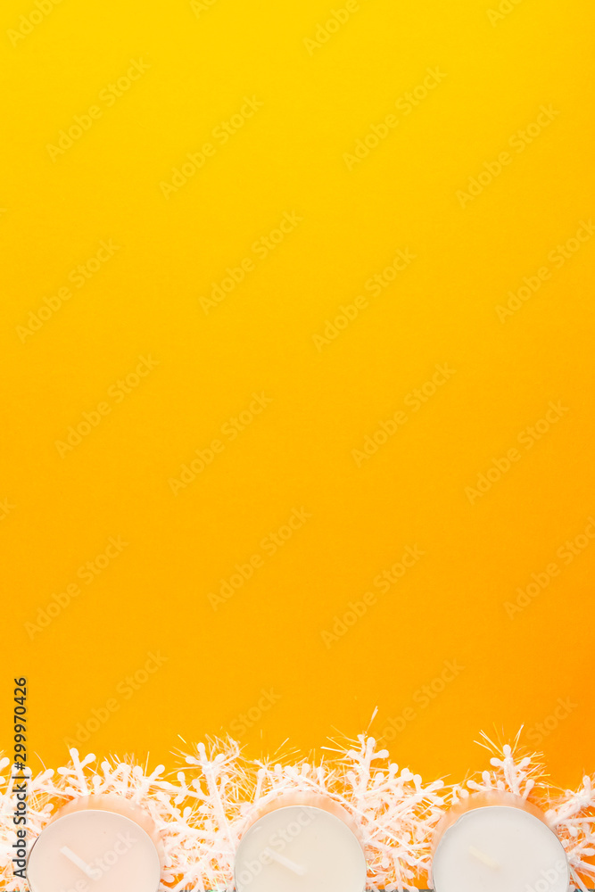 Candles and snowflakes on a orange background. Winter Holiday festive greeting card with copy space for the text. Xmas flat lay concept. Candles and snowflakes on a orange background. Winter Holiday festive greeting card with copy space for the text. Xmas flat lay concept.