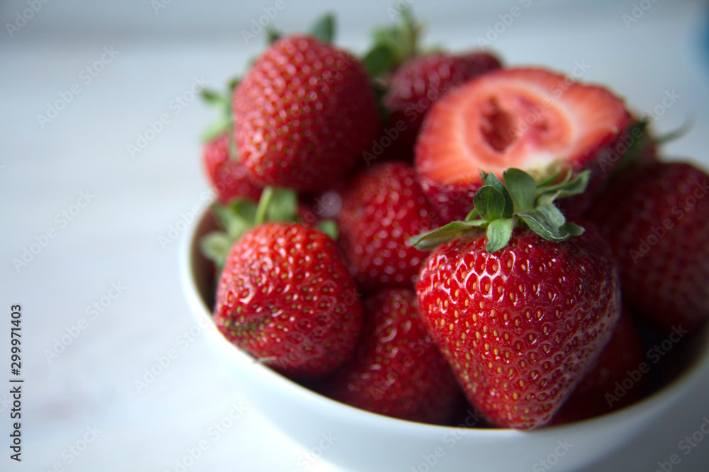 Fresh strawberries in a white bowl on a white table, shallow depth of field Fresh strawberries in a white bowl on a white table, shallow depth of field