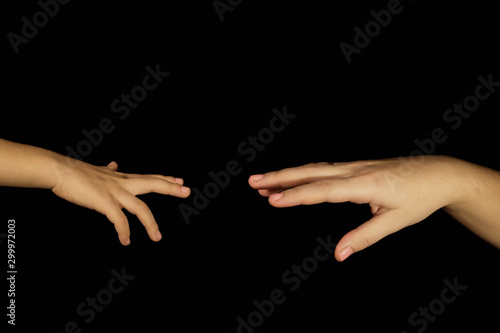 Mother and son hands reach for each other. Isolated women and children palms on a black background. Concept of family relations, help, kindness and spiritual support. Hands close-up and copy space.