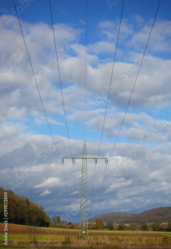 Strommasten hintereinander mit bewölktem Himmel