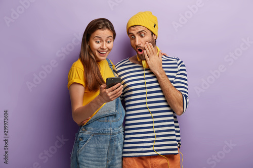 Cheerful young female and male users of modern technologies feels good from s...