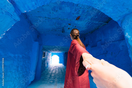 girl in a blue city pulls someone's hand. Morocco © nelen.ru