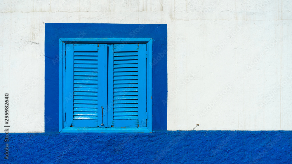 Fototapeta premium Mediterranean white washed house with blue wooden window shutters