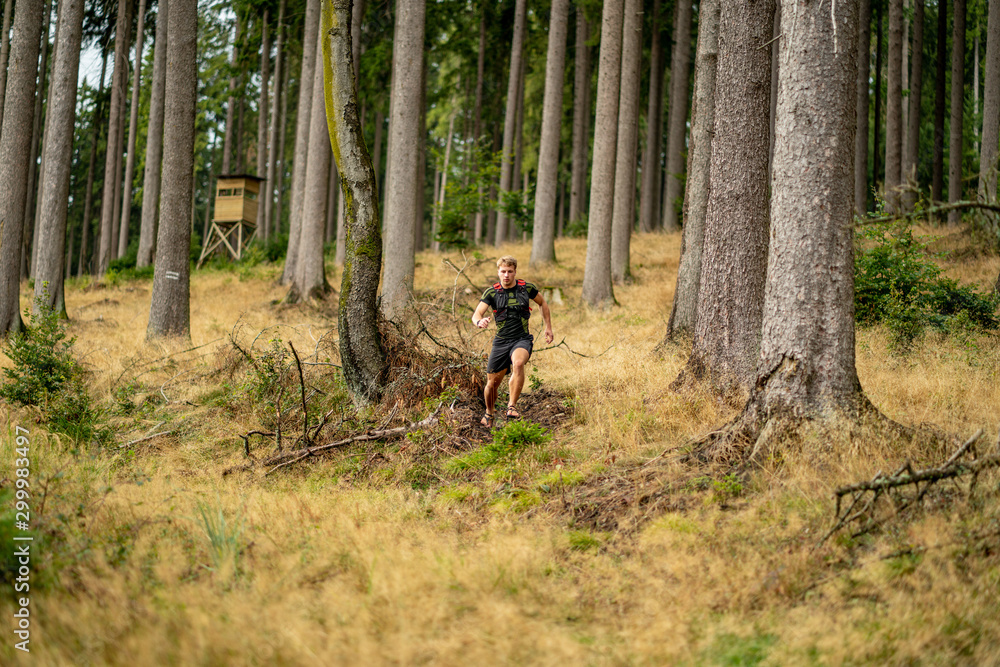 A young athlete in barefoot shoes runs down the mountain. Mountain run. Cross Country Running