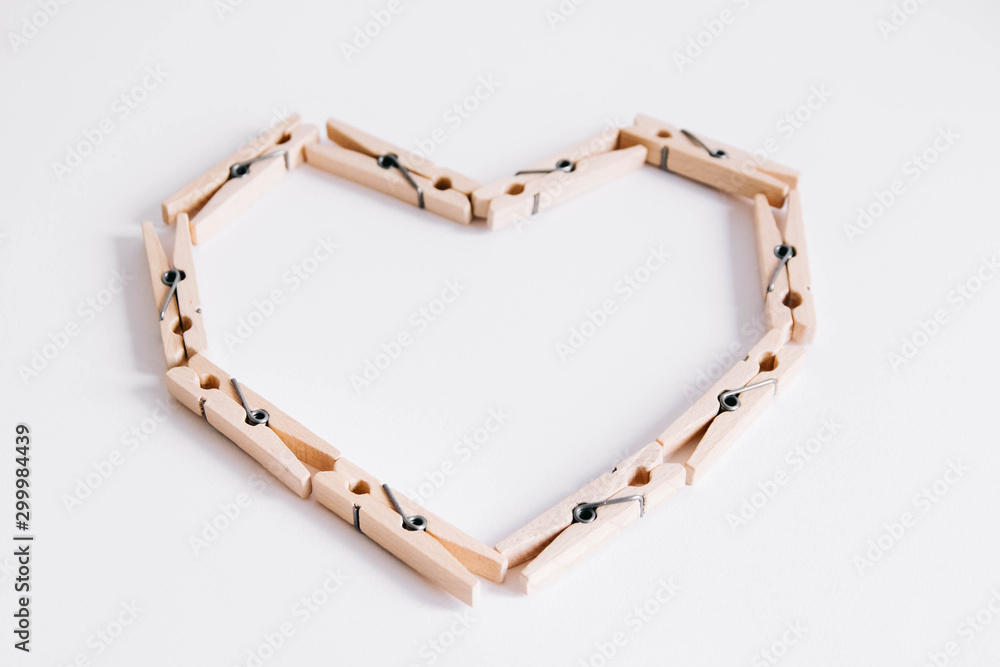 Wooden clothespins on white background which are folded in the form of heart icon. View from above. Wooden clothespins on white background which are folded in the form of heart icon. View from above.