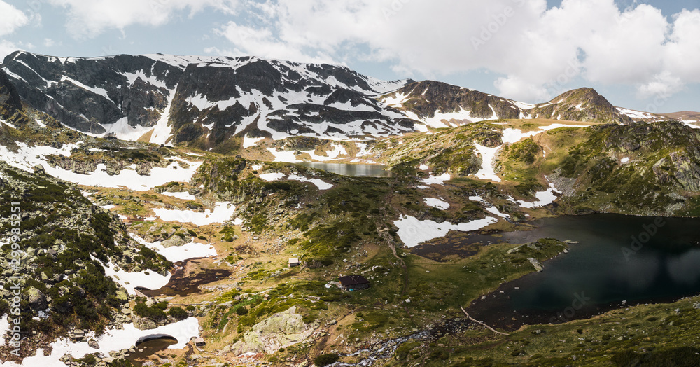 Aerial view of crystal clear blue The Twin Lake (largest of Seven Rila Lakes) with snow covered Rila Mountain during early summer day (near Sofia, Bulgaria, Europe)