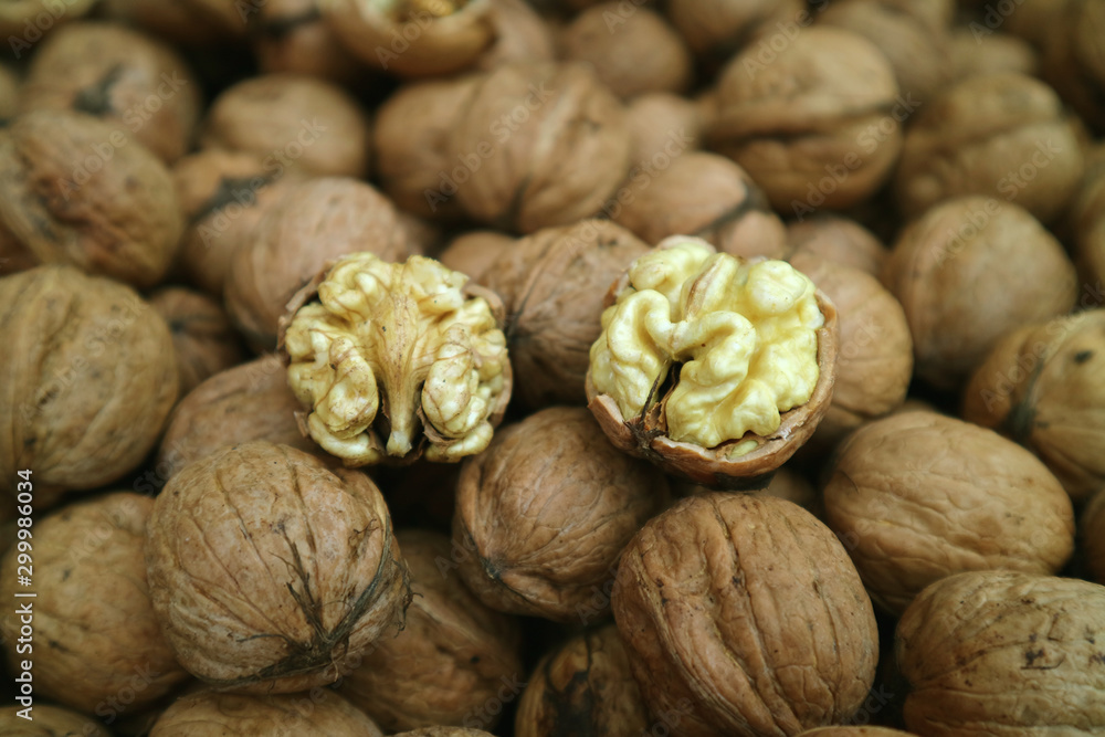 Closeup Raw Walnut's Kernels on the Pile of Walnuts with Nutshells Closeup Raw Walnut's Kernels on the Pile of Walnuts with Nutshells