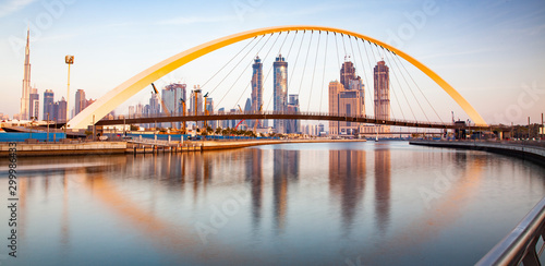 colorful sunset over Dubai Downtown skyscrapers and the newly built Tolerance bridge as viewed from the Dubai water canal