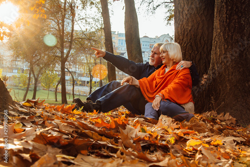 Close up portrait of a happy old woman and man in a park in autumn foliage.