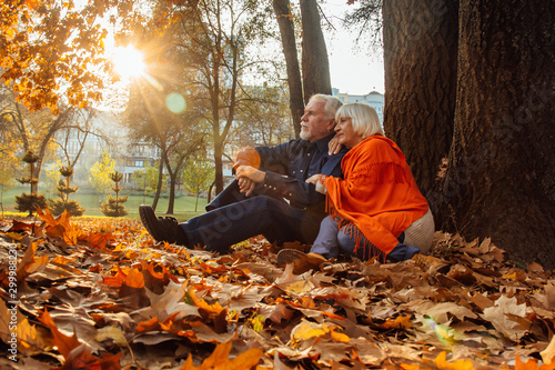 Close up portrait of a happy old woman and man in a park in autumn foliage.