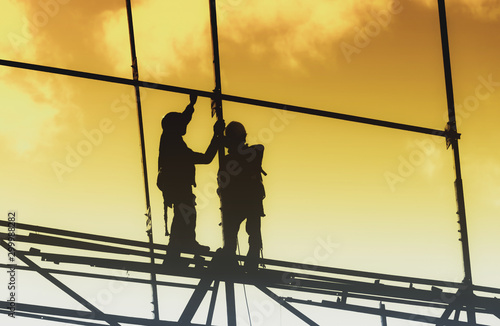 Silhouette City worker, construction crews to work on high ground heavy industry and safety concept over blurred natural background sunset 