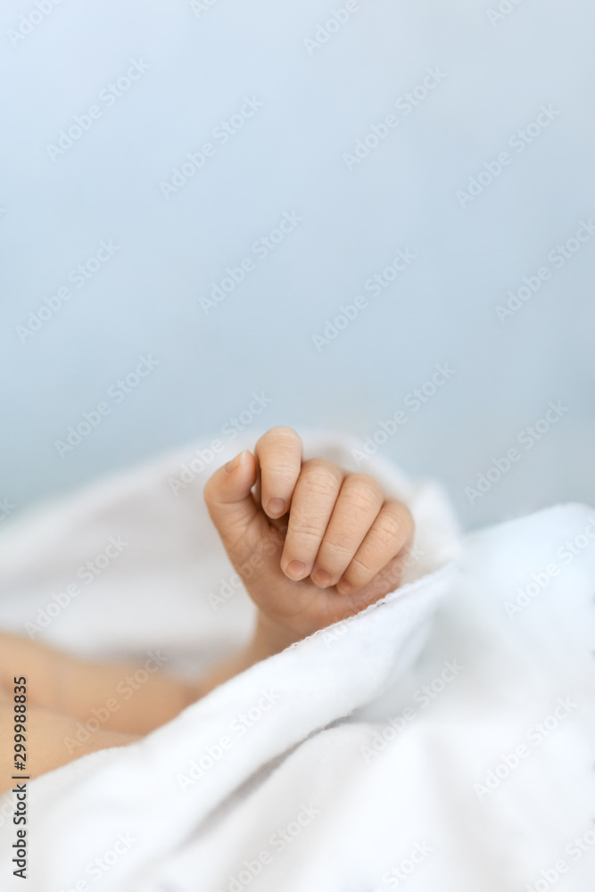 Tiny newborn fist on a white blanket in selective focus, babyhood and family concept Tiny newborn fist on a white blanket in selective focus, babyhood and family concept