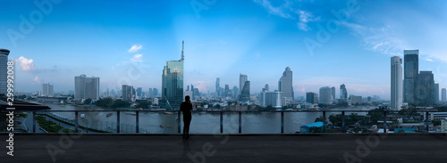 Businessman standing using smart phone on open roof top balcony watching city night view.Business with ambition and vision concept.