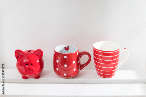 Different red mugs and glasses stand on shelf in the kitchen