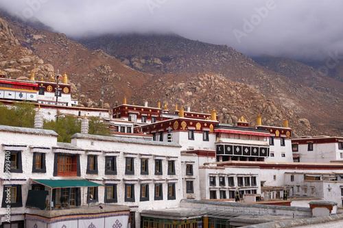 Photography View of brown colored mountains surrounding the white walls of the Drepung Monastery in Lhasa, Tibet