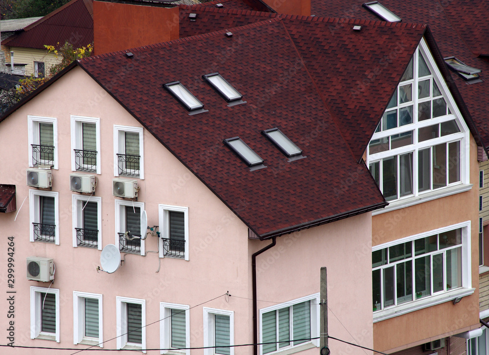 Fototapeta premium The upper part of the building with an attic and a roof covered with shingles.