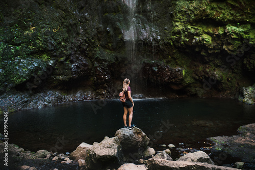 Beautiful forest in Madeira - Portugal. Young traveler standing against waterfall. 