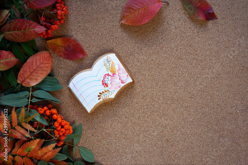 Botanical layout on cork Board: leaves and fruits of mountain ash, autumn leaves and gingerbread on brown background. Homemade notebook and leaves cookies top view photo