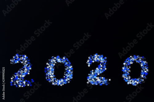 Christmas background. digits 2020 new year from blue sparkles glitter on black background with empty copy space for text. holiday and celebration concept for postcard or invitation. top view 