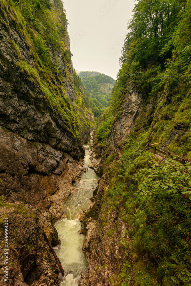 Lammerklamm Gorge in Salzkammergut region of Upper Austria. Blue alpine river between narrow rocky cliffs covered with green vegetation and trees