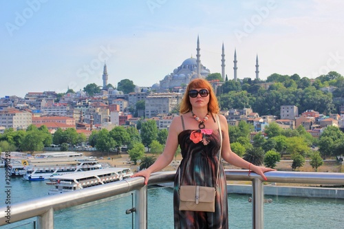 Solo traveling woman in sunglasses with handbag standing on the bridge with Istanbul Suleymaniye mosque background 