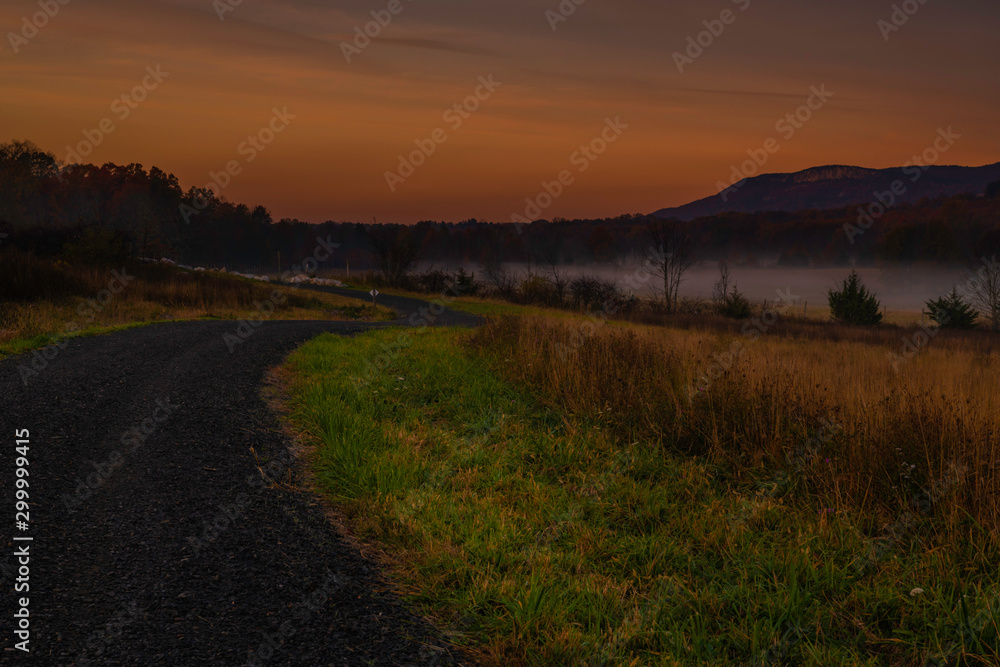 Amazing dreamy sunrise over Shawangunk Mountains, New York, featuring country road passing through farmland on the foreground and mountains on the background on foggy autumn morning Amazing dreamy sunrise over Shawangunk Mountains, New York, featuring country road passing through farmland on the foreground and mountains on the background on foggy autumn morning