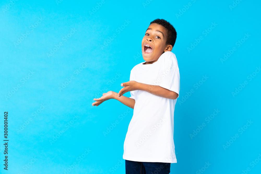 African American boy over isolated blue background with surprise facial expression African American boy over isolated blue background with surprise facial expression