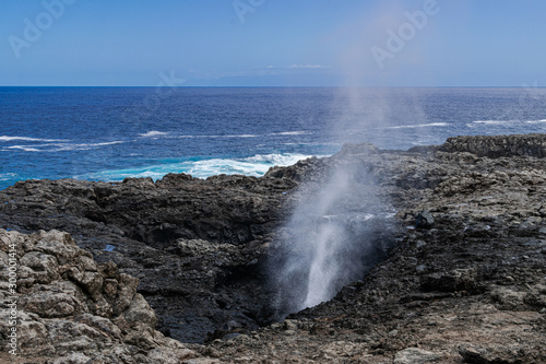 Atlantic ocean salt water blow hole, on volcanic rocks, with sunlight, ocean and blue sky background, in Charco Manso, El Hierro island, Canary islands, Spain