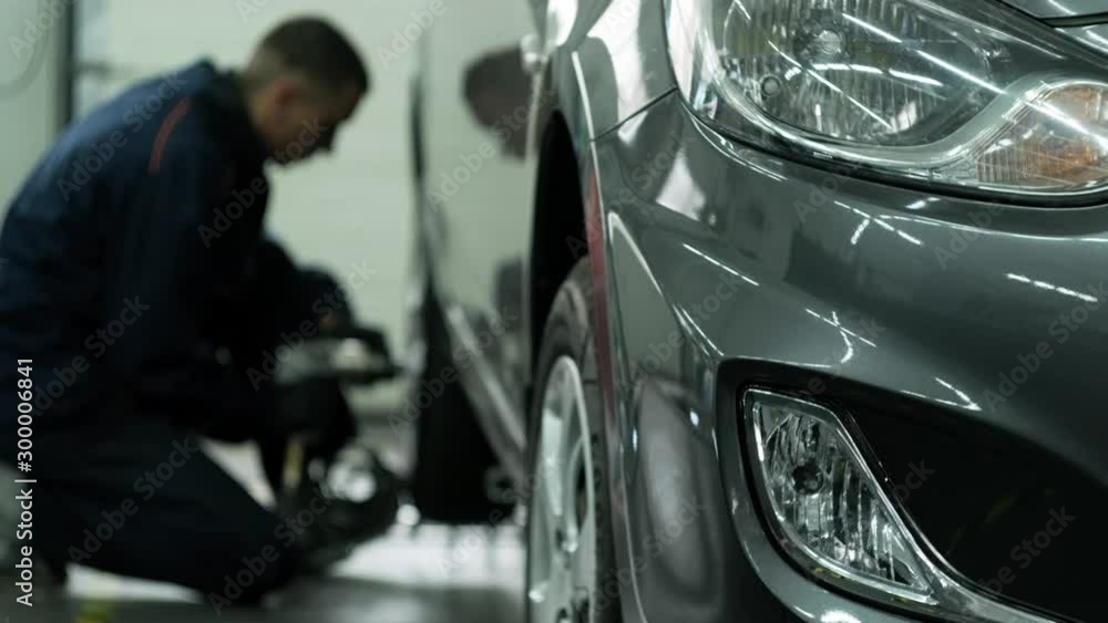 car mechanic screwing or unscrewing car wheel of lifted automobile at repair service station car mechanic screwing or unscrewing car wheel of lifted automobile at repair service station