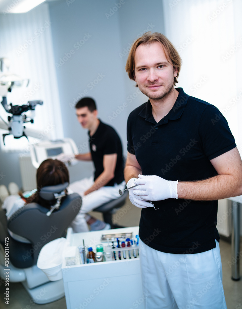 Dentist is posing to the camera at stomatology cabinet. Examining patient's teeth. Modern medical equipment. Oral care concept. Dentist is posing to the camera at stomatology cabinet. Examining patient's teeth. Modern medical equipment. Oral care concept.