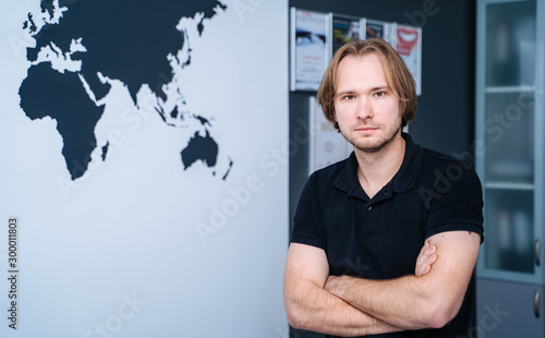 Horizontal portrait of a handsome male dentist posing crosshands at office looking to the camera. Medicine dentistry people and health teeth oral concept. photo