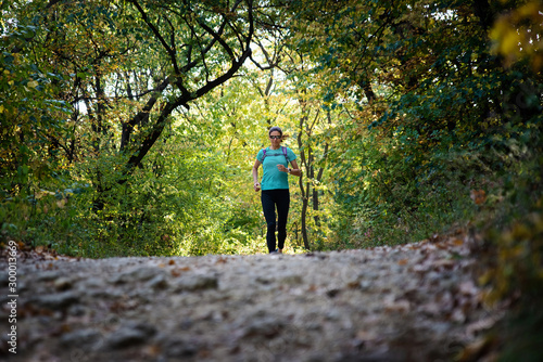 Active woman with sunglasses approaching running on a trail in the nature