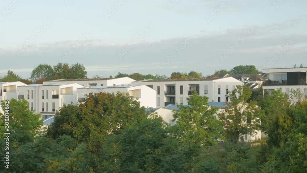 Suburb residential houses panorama sky white clouds horizon over the trees and beige color houses summer at dawn Suburb residential houses panorama sky white clouds horizon over the trees and beige color houses summer at dawn