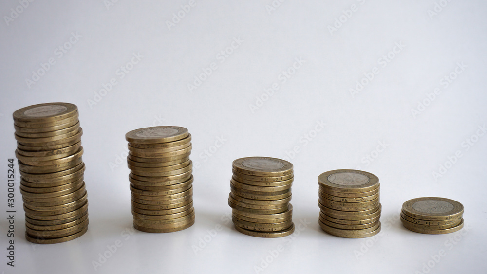 Consuming and decrease concept with metal coins isolated on white background. Spending money for education, summer holiday vacation, new house, new entrepreneurship or basic needs loan. Step by step. Consuming and decrease concept with metal coins isolated on white background. Spending money for education, summer holiday vacation, new house, new entrepreneurship or basic needs loan. Step by step.