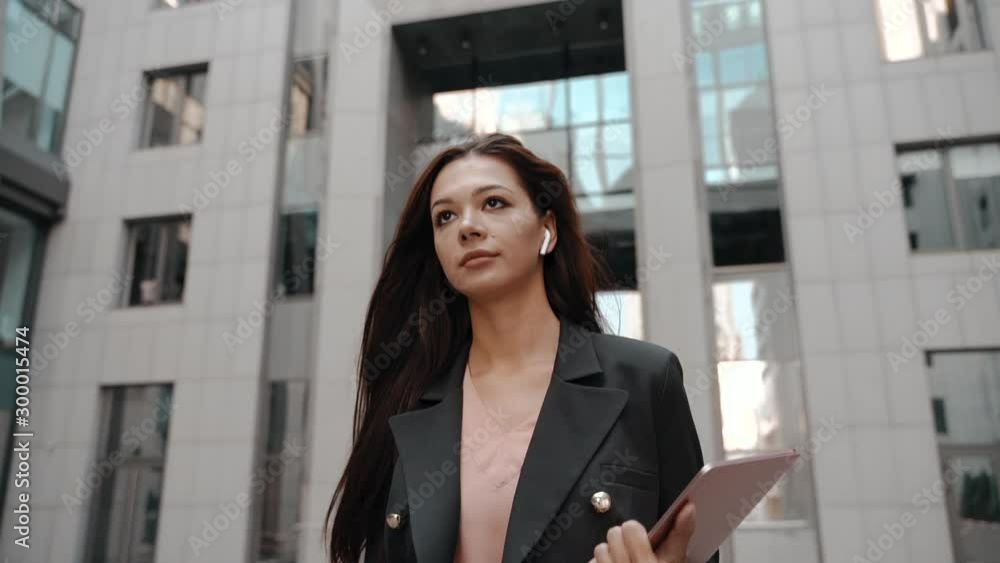 Young adult business lady walking with laptop and earphones Young adult business lady walking with laptop and earphones