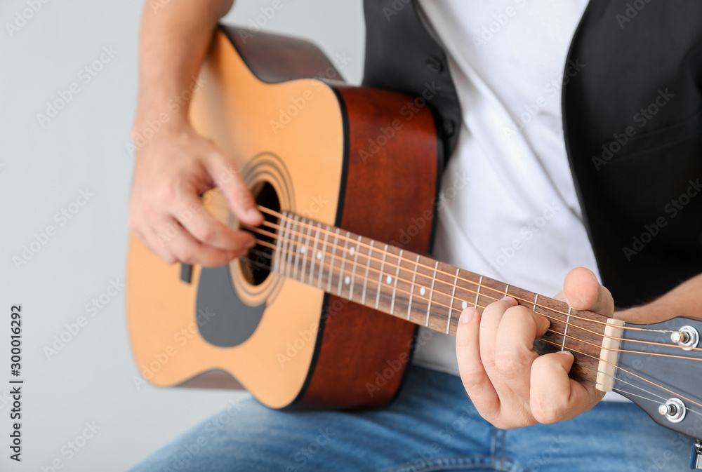 Fototapeta premium Man playing guitar on light background, closeup